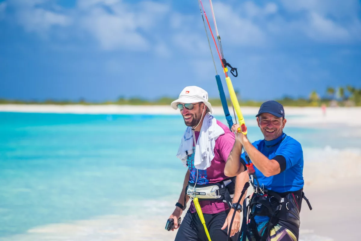 two kiters smiling in front of the spot with blue water